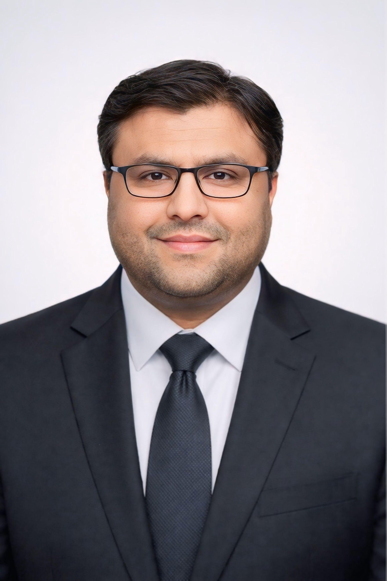 Shahfayaz Khan in a dark suit and tie against a clean studio background