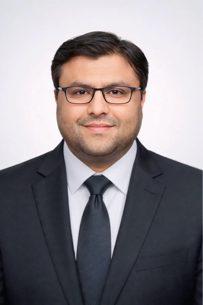 Shahfayaz Khan in a dark suit and tie against a clean studio background